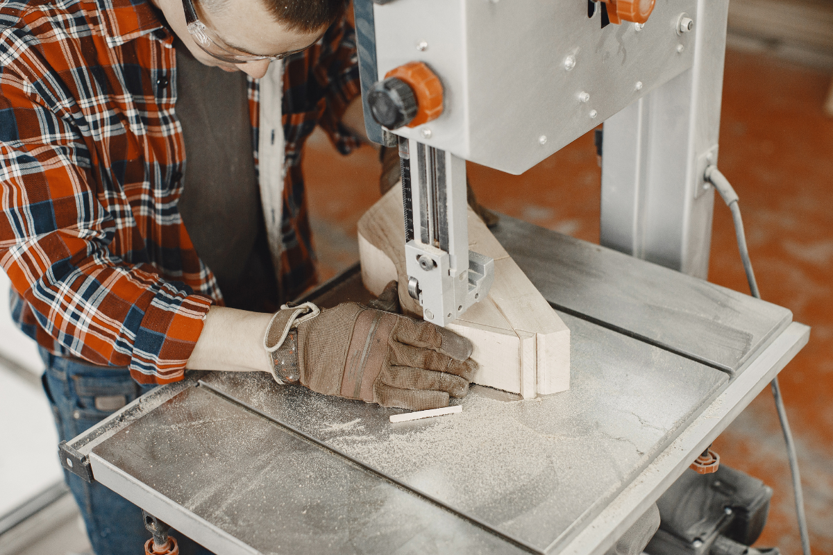 Vertical band saw cutting curved wood piece on workshop table